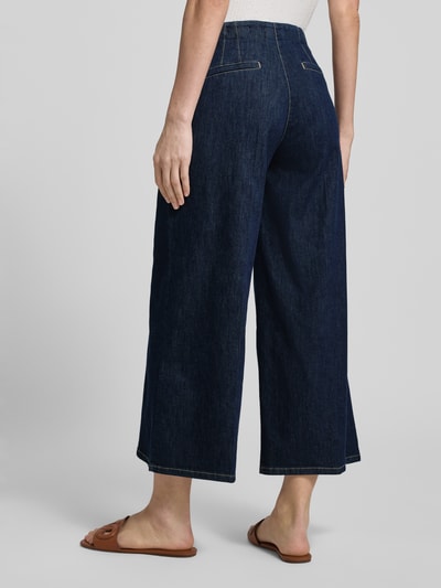 Frauenmodel trägt Wide Fit Jeans mit Lyocell-Anteil Modell 'Jenny' von TONI in Dunkelblau, Baumwoll-Lyocell-Mix, Bundfalten, Eingrifftaschen, Gesäßtaschen, Knopf-Reißverschluss, Ganzkörperansicht Rückansicht.