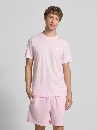 Männermodel trägt T-shirt met labelstitching van Nike in lichtroze, puur katoen, regular fit, ronde hals, ruglengte maat M 73 cm. Ganzkörperansicht van voren.