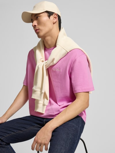 Männermodel trägt t-shirt met logoprint model 'Crew' van Les Deux in roze, puur katoen, recht model, ronde hals, ruglengte bij maat M 74 cm, nahaufnahme bovenlichaam.