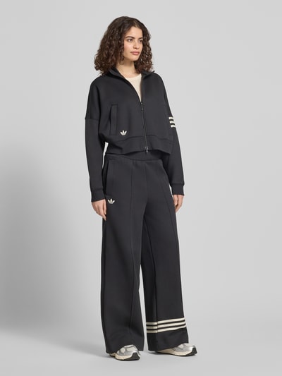 Frauenmodel trägt Wide Leg Sweatpants aus Baumwoll-Mix Modell 'NEUCL' von adidas Originals, Optik: Unifarben, Passform: Wide Leg, Applikation: Logo-Stitching, Kontraststreifen, Bundabschluss: elastisch mit Tunnelzug, Reißverschlusstaschen, Materialverarbeitung: Sweat, Material: Baumwoll-Mix, Ganzkörperansicht von vorne.