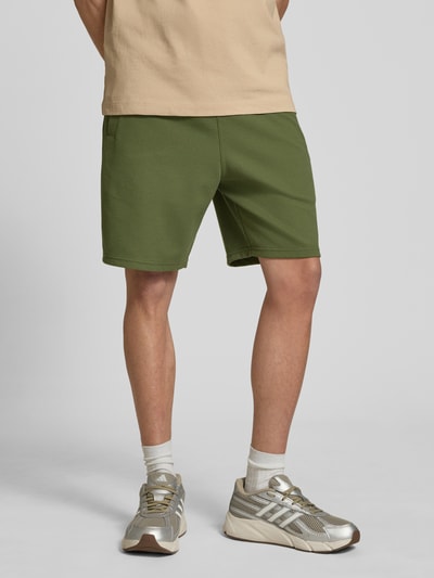 Männermodel trägt Straight Fit Shorts mit Strukturmuster von G-Star Raw in Grün, Elastischer-Material-Mix mit Baumwoll-Anteil, Logo-Detail, Elastischer Bund, Ganzkörperansicht von vorne.
