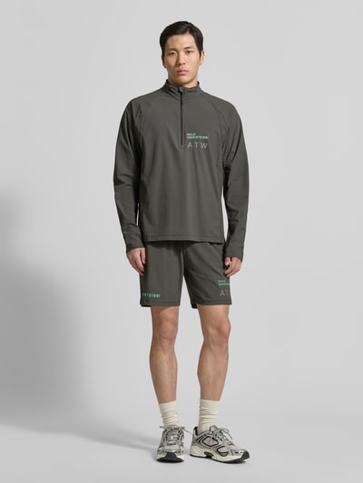 Mannenmodel draagt Funktionsshirt mit Stehkragen und Reißverschluss Modell 'AIR' van HALO in donkergroen, materiaalmix met stretch, regular fit, labelprint, ruglengte maat M: 70 cm, ganzkörperaanzicht van voren.