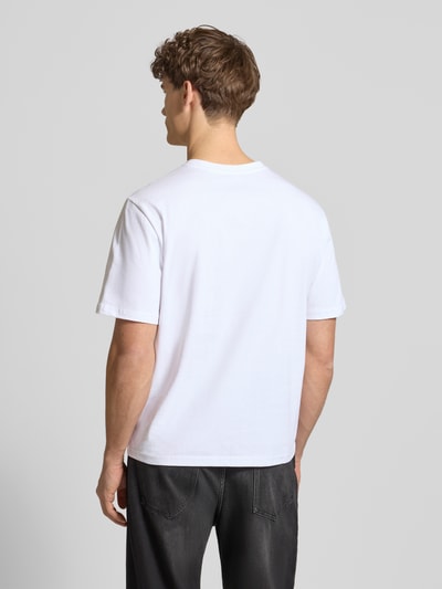 Männermodel trägt Basic T-Shirt mit kleinem Logo-Patch auf der Brust von REVIEW, weiß, gerade Form, Baumwolle, Ganzkörperansicht Rückansicht.