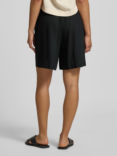 Frauenmodel trägt schwarze Regular Fit Bermudas aus Leinen-Viskose-Mix Modell 'Ina' von Soyaconcept, Rückansicht, feine Struktur. Damen Bermudas, Knopfverschluss, Eingrifftaschen, Bundweite 36 cm, Innenbeinlänge 16 cm, Größe S. Ganzkörperansicht Rückansicht.