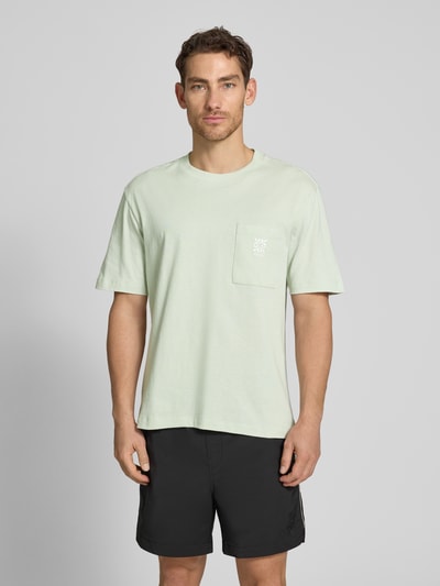 Männermodel trägt Regular Fit T-Shirt aus reiner Baumwolle Modell 'DARRO' von HUGO in Optik: Unifarben, Label-Schriftzug, Rundhals, Ärmelform: Kurzarm, Materialverarbeitung: Jersey, Ganzkörperansicht von vorne.
