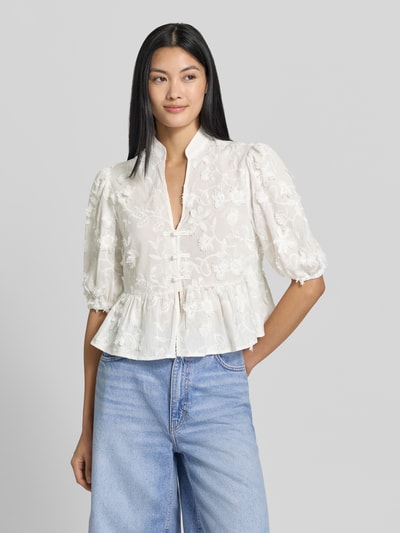 Frauenmodel trägt weiße Regular Fit Bluse mit V-Ausschnitt Modell 'CAPUCHIN' von MANGO aus reiner Baumwolle, florales Muster, Nahaufnahme Oberkörper.