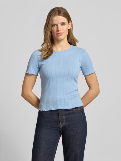 Kobiecy model nosi Slim Fit T-Shirt aus Baumwoll-Mix Modell 'TENNA' von Only, jednokolorowy, okrągły dekolt, krótki rękaw, zakończenia frill, mieszanka bawełny, jasnoniebieski, strukturalna faktura, Ganzkörperansicht von vorne.