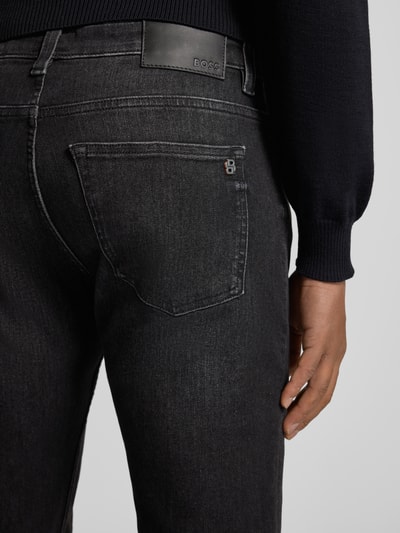 Männermodel draagt Slim fit Jeans uit katoenmix Model 'DELAWARE BO S.ELECTION' van BOSS, denimlook, labelpatch, 5-pocketmodel, knoop- en ritssluiting, met studs, zwarte tinten, detailrijke textuur, katoenmix, close-up achteraanzicht.