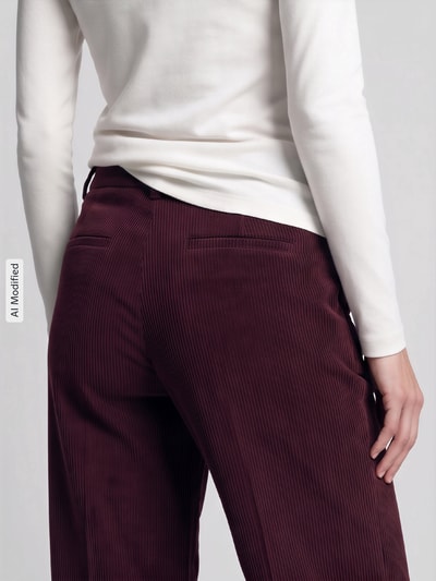 Frauenmodel trägt Relaxed Fit Cordhose seitliche Eingrifftaschen 'ALEXIS' von CAMBIO in Dunkelrot, feine Rippenstruktur, Nahaufnahme Rückansicht, KI-modifiziertes Bild.