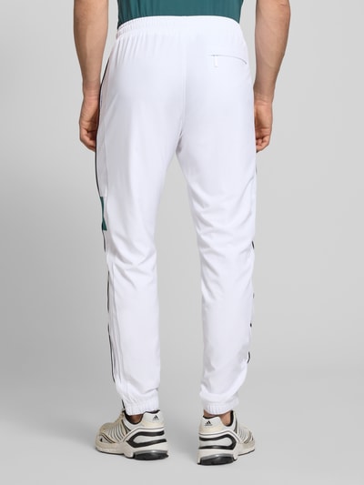 Männermodel trägt sweatpants met logostitching model 'CASPIO' van SERGIO TACCHINI in wit materiaalmix met stretch, elastische band met trekkoord, zij-steekzakken, nauwsluitend model; binnenbeenlengte maat M 78 cm, elastische boordjes, model vanuit rugaanzicht.