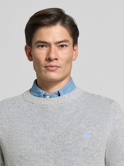 Männermodel trägt Slim Fit Strickpullover aus reiner Wolle mit Label-Stitching von MCNEAL, graue Farbe, Nahaufnahme Oberkörper.