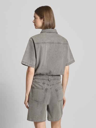 Frauenmodel trägt Regular Fit Playsuit in Denim-Optik Modell 'Fillipa' von JJXX aus Reine Baumwolle, 5-Pocket-Design, Kurzärmelig, Umlegekragen, Knopfleiste, Brusttasche, Rückenlänge bei Größe S: 93 cm, Brustweite: 52 cm, Ärmellänge: 26 cm, Gesamtlänge: 88 cm, Innenbeinlänge: 17 cm, einfarbig grau mit strukturierter Oberfläche, Ganzkörperansicht Rückansicht.
