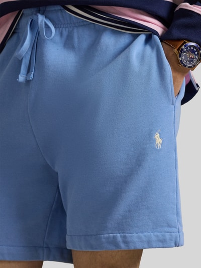 Mężczyzna nosi Regular Fit Sweatshorts aus reiner Baumwolle od Polo Ralph Lauren w jednolitym jasnoniebieskim kolorze, logo-stitching, boczne kieszenie, tylna kieszeń, elastyczny pas ze sznurkiem, materiał sweat z czystej bawełny, detalami złagodzona tekstura; zbliżenie na biodra i kieszeń.