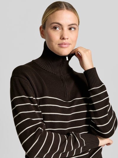 Frauenmodel trägt Regular Fit Pullover aus reiner Baumwolle von MANGO in Dunkelbraun mit Streifen, Strick-Optik, Troyer-Kragen, Nahaufnahme Oberkörper.