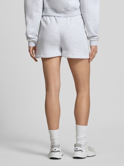 Frauenmodel trägt Regular Fit Sweatshorts mit Spitzenbesatz von Review in hellgrau, Material-Mix mit Baumwoll-Anteil, Ganzkörperansicht Rückansicht.