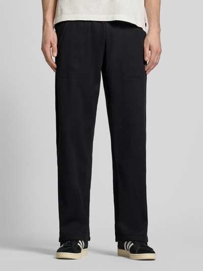 Männermodel trägt Straight Fit Sweatpants mit elastischem Bund Modell 'Essentials' von adidas Originals, schwarz, Strukturmuster, Baumwoll-Mix, Ganzkörperansicht von vorne.