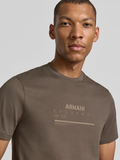 Männermodel trägt Slim Fit T-Shirt aus puur katoen met logoprint van Armani Exchange in taupe, heren, met korte mouwen, nahaufnahme bovenlichaam.