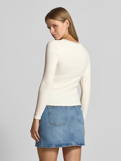 Frauenmodel trägt Slim Fit Langarmshirt aus Baumwoll-Mix Modell 'SARA SHARAI' von ONLY in Creme, kombiniert mit Jeansrock, Ganzkörperansicht Rückansicht. Damen Langarmshirt von ONLY.