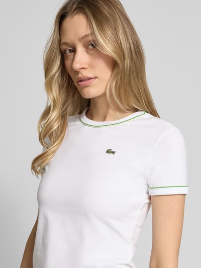 Frauenmodel trägt Slim Fit T-Shirt aus Baumwoll-Mix von Lacoste, unifarben mit Logo-Stitching, Kontrast-Paspel, Nahaufnahme Oberkörper.
