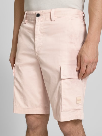 Männermodel trägt Relaxed Fit Cargoshorts aus Baumwoll-Mix Modell 'SISLA' von BOSS Orange in Unifarbe mit Label Patch, Nahaufnahme Oberschenkel.