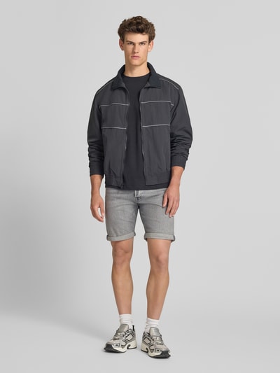 Männermodel trägt Regular Fit Jeansshorts mit Umschlag Modell 'RICK' von Jack & Jones aus Baumwoll-Elasthan-Mix, Eingrifftaschen, Ganzkörperansicht von vorne. Bundweite bei Größe M: 42 cm, Innenbeinlänge bei Größe M: 21 cm.