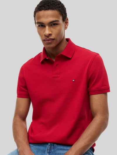 Männermodel trägt Regular Fit Poloshirt aus Baumwoll-Mix von Tommy Hilfiger in Rot, glatte Struktur, Nahaufnahme Oberkörper. Herren Poloshirt