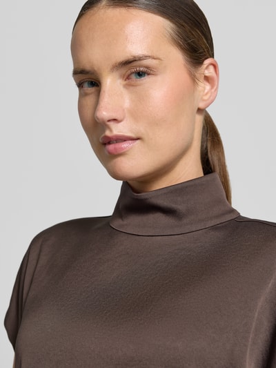 Frauenmodel trägt Blusentop mit Stehkragen Modell 'ALARIA' von DRYKORN in Braun, feine Struktur, Material-Mix mit Stretch, Nahaufnahme Oberkörper.