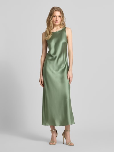 Frauenmodel trägt Cocktailkleid mit tiefem Rückenausschnitt von GUIDO MARIA KRETSCHMER WOMAN, satinierter olivgrüner Stoff, Midikleid, körpernaher Schnitt, Rundhalsausschnitt, breite Träger, Rückseite V-Ausschnitt, Ganzkörperansicht von vorne.