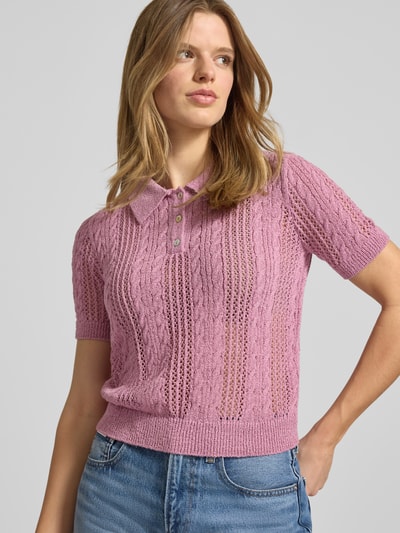 Frauenmodel trägt Slim Fit Poloshirt in Strick-Optik Modell 'Ajour' von Review, rosa mit Loch-Optik, Kurzarm, Nahaufnahme Oberkörper