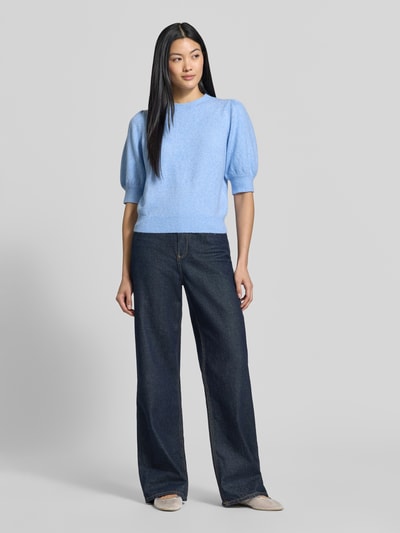 Frauenmodel trägt Regular Fit Pullover mit Puffärmeln von VERO MODA in Hellblau, kombiniert mit dunkelblauer weiter Jeans, Ganzkörperansicht von vorne.