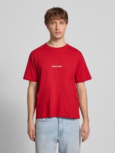 Männermodel trägt T-Shirt mit Label-Stitching Modell 'NORREBRO' von Jack & Jones in Rot, reine Baumwolle, Regular Fit, Ganzkörperansicht von vorne.