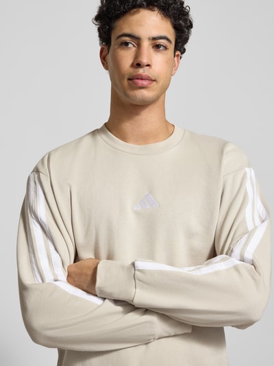 Männermodel trägt Sweatshirt mit Label-Stitching von adidas Sportswear im Baumwoll-Mix mit Viskose-Anteil, Nahaufnahme Oberkörper.