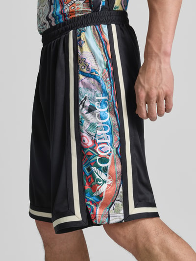 Männermodel trägt Shorts aus Mesh mit Kontraststreifen von COLUCCI, elastischer Bund, gerader Schnitt, Nahaufnahme Oberschenkel.