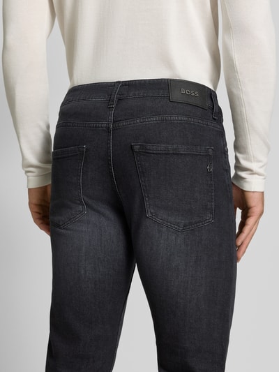 Männermodel trägt Slim Fit Jeans aus Baumwoll-Mix Modell 'Delaware' von BOSS in dunklem Grau, Herren Straight Fit Jeans, Ganzkörperansicht Rückansicht.