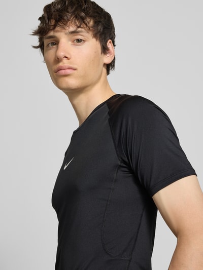 Männermodel trägt T-Shirt mit Logo-Print und Rundhalsausschnitt von NIKE TRAINING, Slim-Fit, Raglanärmel, schwarze Farbe, Nahaufnahme Oberkörper. Rückenlänge Größe M: 72 cm.