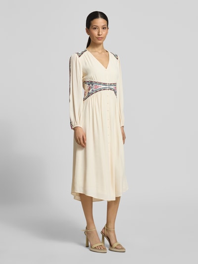 Frauenmodel trägt Regular Fit Midikleid aus reiner Viskose Modell 'Tina' von Bash in Creme mit Zier-Stitching, Langärmelig, Knopfleiste, Ganzkörperansicht von vorne.