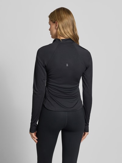 Frauenmodel trägt Funktionsshirt mit Reißverschluss und Logo Modell 'Tempo' von NIKE TRAINING in Schwarz, Slim Fit, Rückenansicht Ganzkörperansicht.