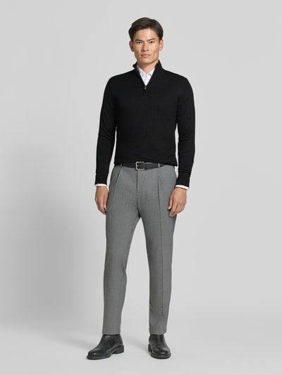 Männermodel trägt Troyer mit Label-Applikation von MARKUP, schwarz, Viskose-Mix, gerader Schnitt, Troyer-Kragen, Ganzkörperansicht von vorne.