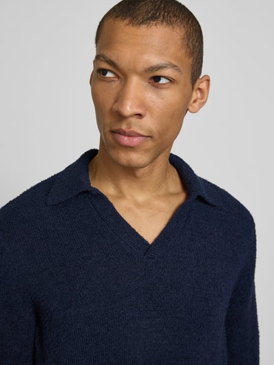 Männermodel trägt Regular Fit Poloshirt aus Bio-Baumwoll-Mix Modell 'BOUCLE' von Armedangels in Dunkelblau, Bouclé-Strick, Nahaufnahme Oberkörper.