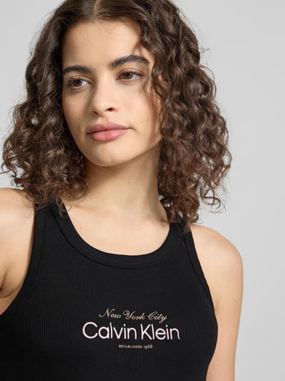 Kobieta modelka nosi top z mieszanki bawełny o dopasowanym kroju Calvin Klein Jeans Top mit Label-Stitching Modell 'CONTOUR', dekolt w łódkę, wyhaftowane logo, damski top, długość tyłu dla rozmiaru S: 48 cm, zbliżenie na górę torsu