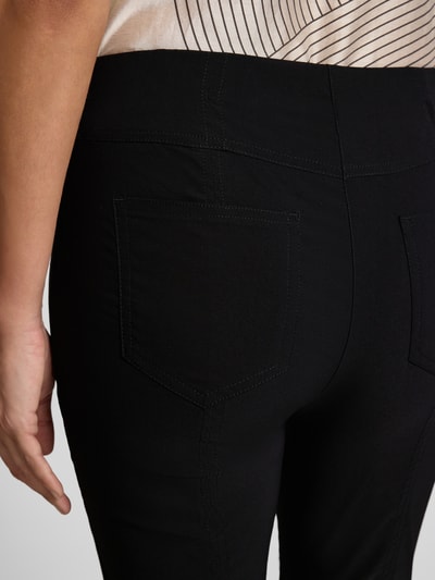 Frauenmodel trägt Caprihose aus Viskose-Mix Modell 'Igor3' von STEHMANN in Schwarz, glatter Stoff, Detailaufnahme Rückansicht, Slim Fit, elastischer Bund.