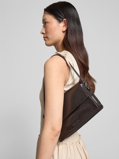 Frauenmodel trägt Umhängetasche aus Leder mit Logo-Prägung Modell 'AUDREY' von LIEBESKIND BERLIN, beschichtet, Ganzkörperansicht von vorne. Hauptfach mit Magnetverschluss, langer Tragegriff, verstellbarer Schultergurt, Maße: Breite 25 cm, Länge 17 cm, Tiefe 9 cm, Schulterriemenlänge 60 cm.