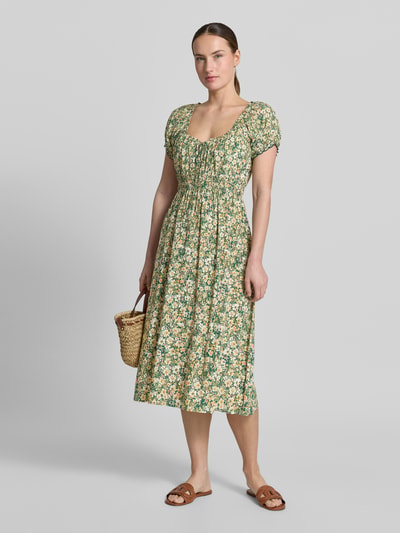 Frauenmodel trägt Midikleid aus Viskose mit Rüschenärmeln von Apricot, florales Muster, Taillierter Schnitt, Ganzkörperansicht von vorne. Rückenlänge bei Größe S: 113 cm, Brustweite bei Größe S: 29 cm, Ärmellänge bei Größe S: 16 cm, mit Rundhalsausschnitt, Schnürung, Smok-Details.