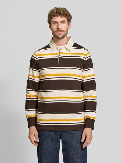 Mannenmodel draagt Regular Fit poloshirt uit puur katoen van GANT in bruin, geel en wit met horizontale strepen, volledig lichaam van voren.