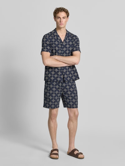 Mannenmodel draagt Relaxed Fit Stoffshorts uit katoen van s.Oliver RED LABEL met donkerblauw en beige patroon, geheellichaamsvooraanzicht.