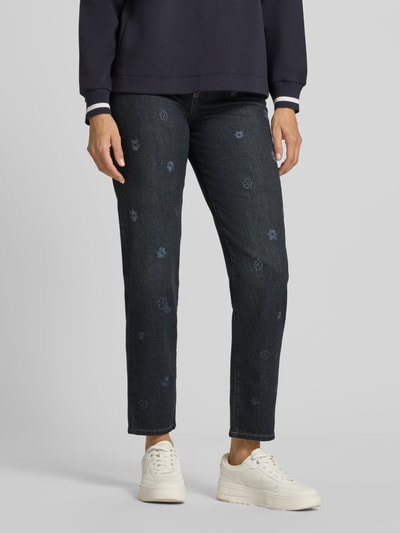 Frauenmodel trägt Straight Fit Jeans aus reiner Baumwolle von Marc Cain mit floralem Allover-Stitching, 5-Pocket-Design, dunkelblau, Nahaufnahme Unterkörper, Kontext: Damen Jeans, reine Baumwolle, Knopf- und Reißverschluss, Bundweite 36 cm, Innenbeinlänge 74 cm.