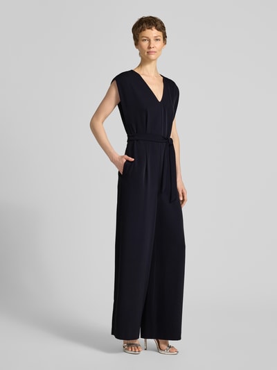 Frauenmodel trägt Jumpsuit mit V-Ausschnitt und Bindegürtel von comma in Dunkelblau, Regular Fit, Material-Mix mit Stretch, Ganzkörperansicht von vorne.