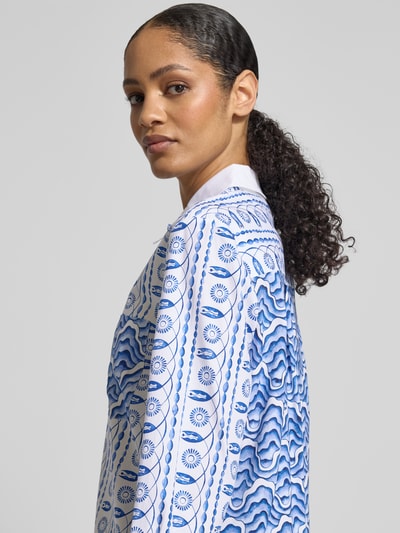 Vrouwenmodel draagt Regular Fit Bluse im Allover-Look mit Brusttasche van HERZENS in katoen-elastaan mix met blauwe print, detailopname van de bovenkant.