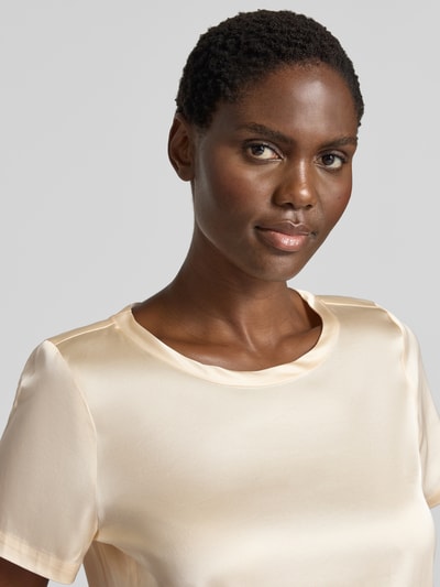Frauenmodel trägt Blusenshirt aus Satin mit Rundhalsausschnitt von Christian Berg Woman Selection in Creme, Regular Fit, Nahaufnahme Oberkörper.