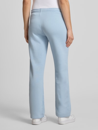 Frauenmodel trägt hellblaue Sweatpants mit elastischem Bund Modell 'Iconic' von Gina Tricot aus Baumwoll-Mix, Relaxed Fit, Ganzkörperansicht Rückansicht.